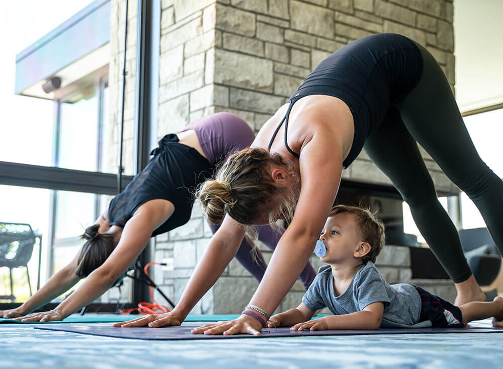two women doing downward-facing dog with a baby